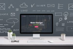 Modern computer screen displaying web design services with creative workspace background.