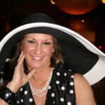 Windward Design Group - Meet Tina Marker Tina Marker wearing a large black and white hat, smiling at an indoor event.