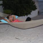 Tina Marker on hammock by the beach at sunset Tina Marker lying on hammock enjoying seaside relaxation and scenic views.