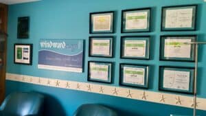 Windward Design Group Certificates Collection of framed certificates on a teal wall at Windward Design Group office.