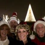 Holiday Celebration with Tina Marker and Family Festive holiday photo of Tina Marker and family wearing Santa hats at night with Christmas lights an.